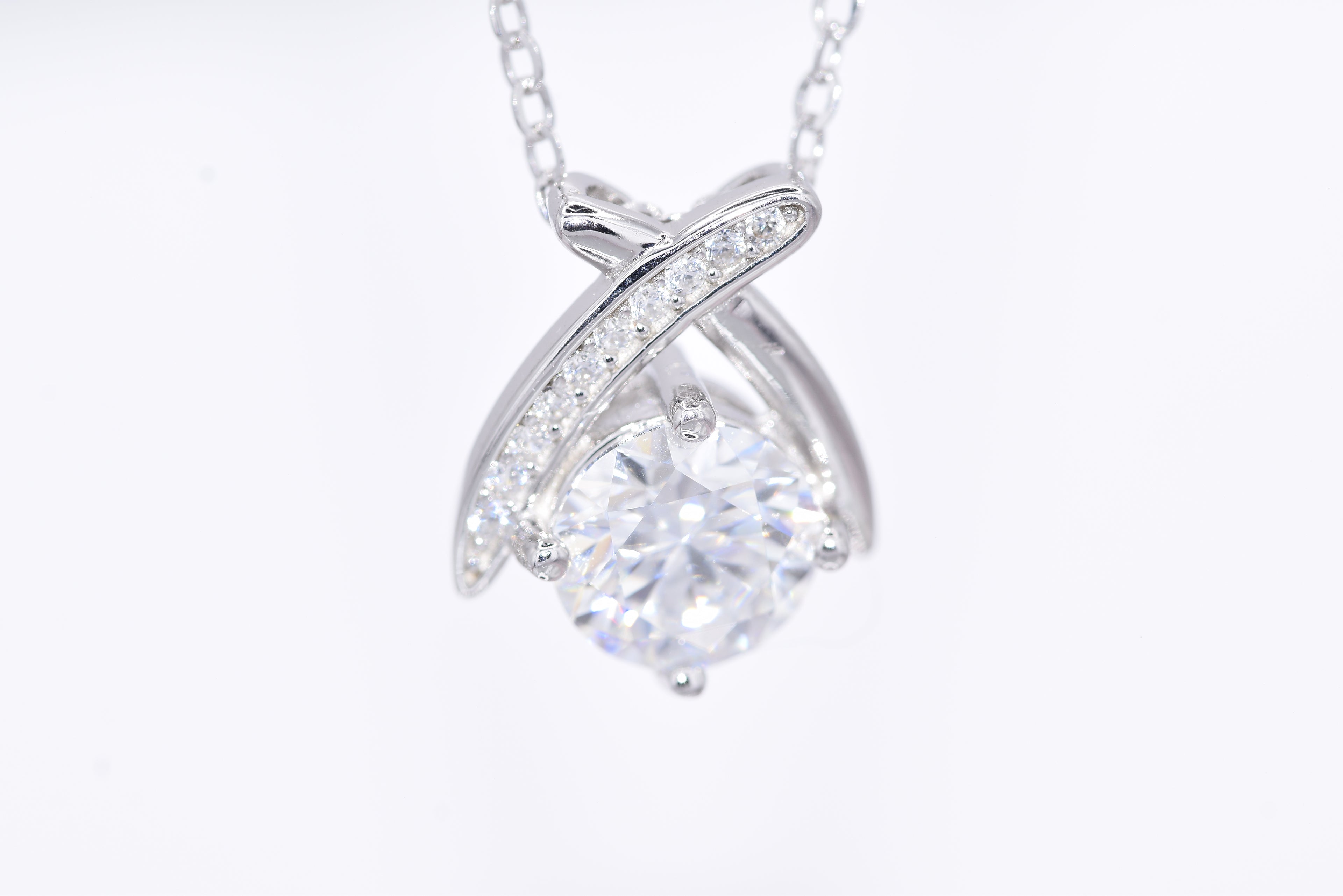 Close-up 1ct VVS1 round brilliant moissanite pavé ribbon wrap pendant rhodium silver — Byrall Jewellery